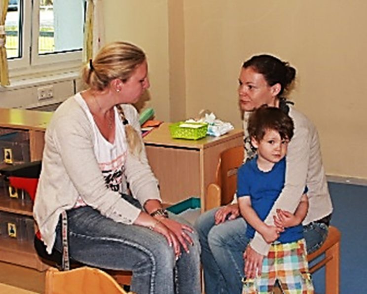 Eine Mutter mit ihrem Kind im Gespräch mit einer Erzieherin